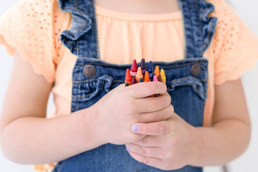 child holding crayons
